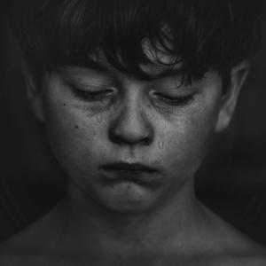 Foto em preto e branco aproximada da face de uma criança com lágrimas no rosto