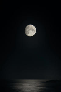 Foto de lua cheia acinzentada sobre o mar calmo